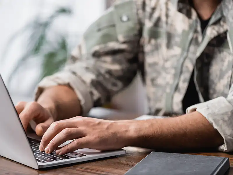 Military person in uniform using a laptop
